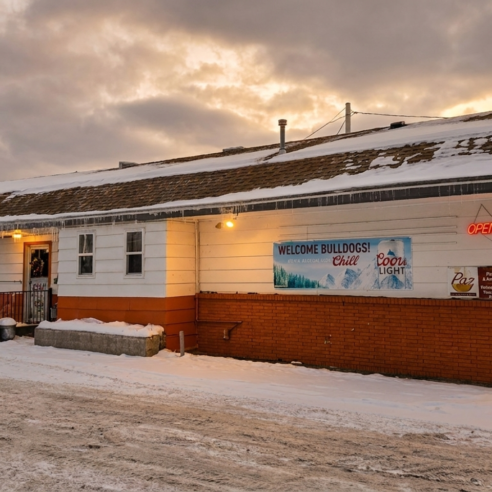 Paz Pub & Grill exterior in winter, with snow on the roof and ground under a cloudy sky.