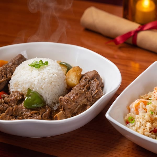 Steaming beef stew with rice and vegetables, alongside a bowl of shrimp fried rice.