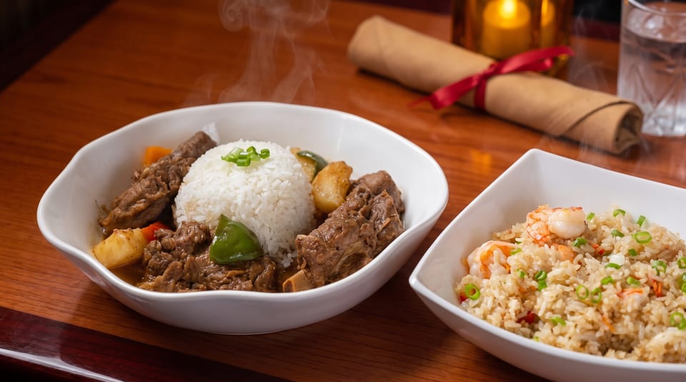 Steaming beef stew with rice and vegetables, alongside a bowl of shrimp fried rice.