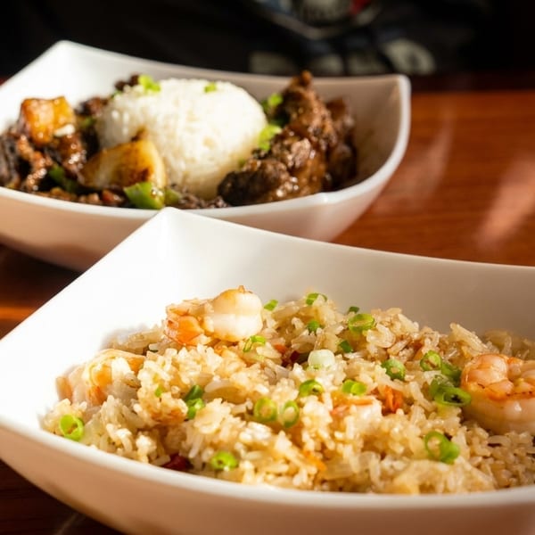 Two bowls of Asian cuisine: shrimp fried rice and beef with white rice and vegetables.