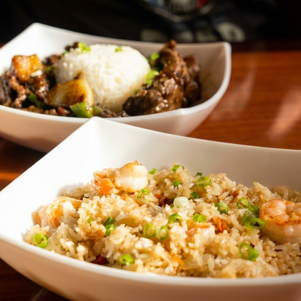 Two bowls of Asian cuisine: shrimp fried rice and beef with white rice and vegetables.